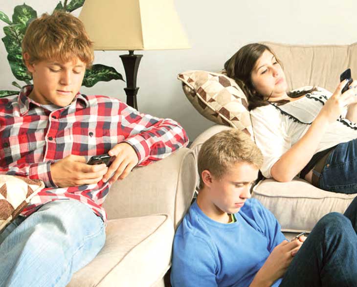 Nell’immagine 3 adolescenti seduti vicini ma isolati perché tutti alle prese con il proprio smartphone
